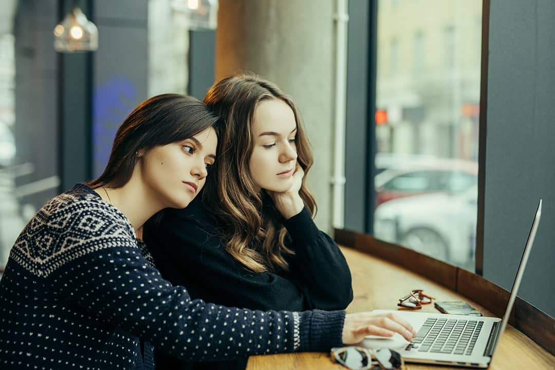 Young adults checking AI digital platforms for relationship advice from a laptop.